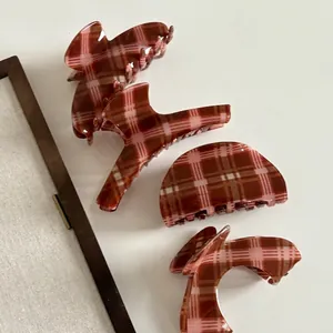 Set of four vintage red-brown plaid claw clips in various shapes on white background