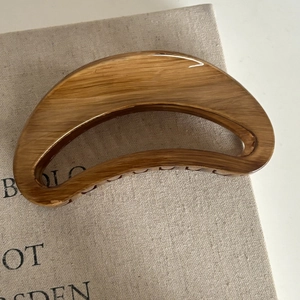 Large crescent hair claw with vintage wood grain texture for elegant hairstyling