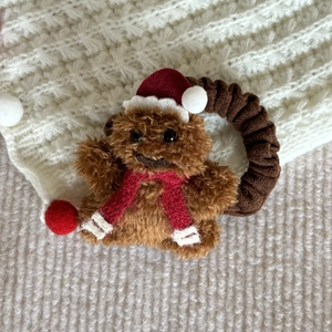 Detail of plush Christmas bear hair scrunchie with festive red hat and scarf accessory
