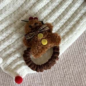 Brown plush bear hair tie with plaid bow and yellow buttons on white knit background