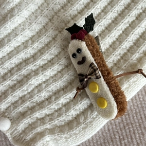 Close-up of plush gingerbread man Christmas hair clip on soft knit background