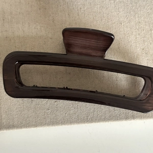 Close-up of a large dark brown hair claw clip with a vintage wood grain texture design