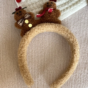 Detailed view of gingerbread man plush headband with festive red scarf and bow accents