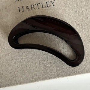Macro detail of glossy dark brown hair claw clip with large semi-circle hollow design