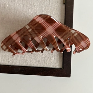 Close-up of a large brown plaid hair claw clip with vintage tartan pattern and glossy finish