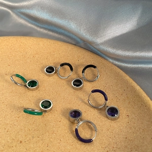 Vista detallada de los aretes de aro con circonitas en esmeralda, negro y morado