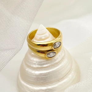Macro shot of two vintage gold-plated stainless steel rings with oval zircon on a seashell