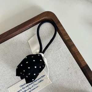 Élastique à cheveux tulipe à pois noir et blanc avec nœud en satin sur plateau bois