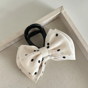 Elegant cream bow hair claw clip with black polka dots shown from a 45-degree angle