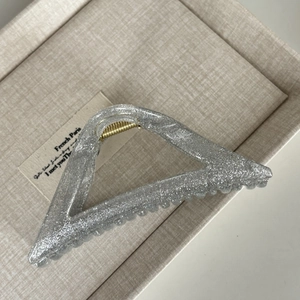 Macro shot of large triangular hair claw with silver sequins and gold metal spring