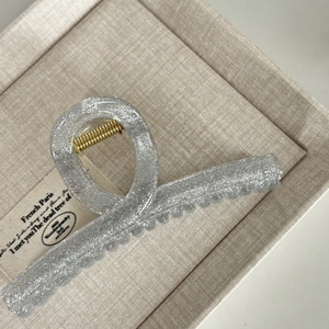 Detail of silver glitter hair claw with gold spring and interlocking teeth on jewelry box
