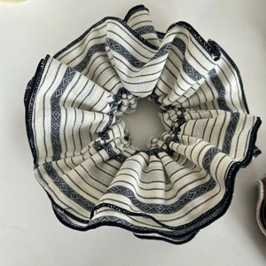 Close-up of oversized striped fabric scrunchie with navy blue and cream woven patterns