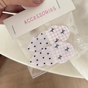 Dettaglio di fermagli rosa a forma di nuvola con pois e fiocchi nella confezione