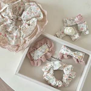 Détail de chouchous fleuris et pinces à cheveux en dentelle avec rose sur plateau blanc