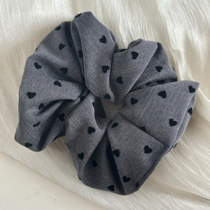 Grey French style scrunchie with black heart pattern on elegant off-white silk background
