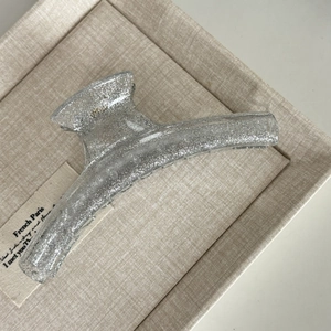Macro detail of large silver glitter hair claw clip inside a beige textured gift box