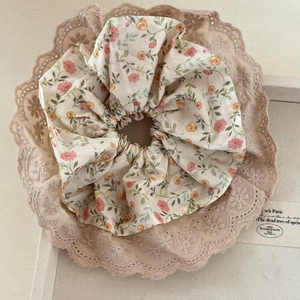 Chouchou floral avec bordure en dentelle marron clair sur un plateau à bijoux