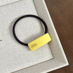 Close-up of yellow acetate hair tie with France Handmade text on elastic band