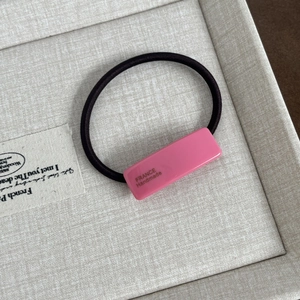 Detail of pink resin hair tie with handmade inscription on a black elastic band