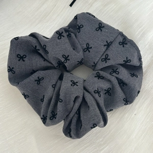 Detailed view of gray satin scrunchie fabric featuring black bow patterns and soft pleats