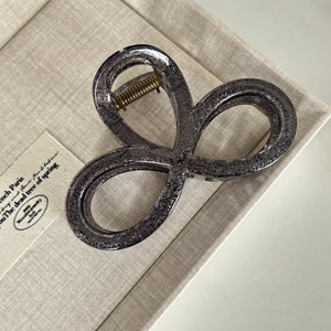 Detail view of large silver glitter hair claw clip with artistic triple loop design