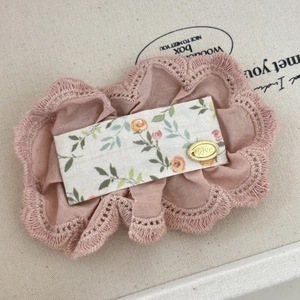 Détail de l'élastique en dentelle rose avec motif floral et médaillon doré Love