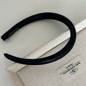 Minimalist wide black satin headband with handmade label on a beige texture box