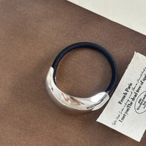 Close-up of a high-elastic black hair tie with a polished silver crescent metal piece