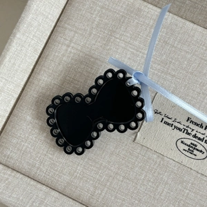 Detail of a black cutout bow hair clip with a light blue ribbon on a jewelry box