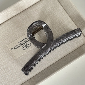 Detail of large dark grey glitter hair claw clip with golden spring on fabric background