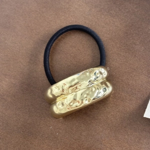 Detail view of high-elasticity hair tie with gold hammered texture metal cylinder ornament