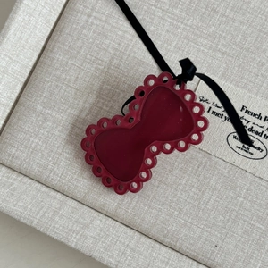 Detailed view of a dark red bow accessory with hollow cutouts and a thin black ribbon