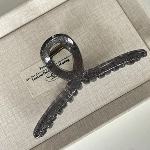 Close-up of a large twisted hair claw clip in dark grey with silver glitter accents