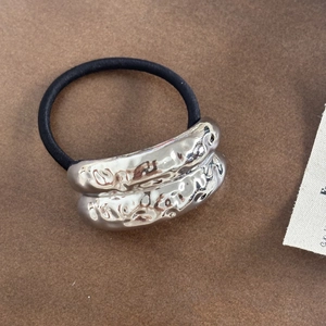 Detailed macro view of black high-elastic hair tie with irregular liquid silver metal piece