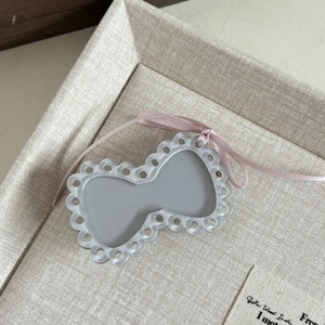 Detail of grey resin bow hair clip with wavy hollow lace and pink ribbon on fabric tray