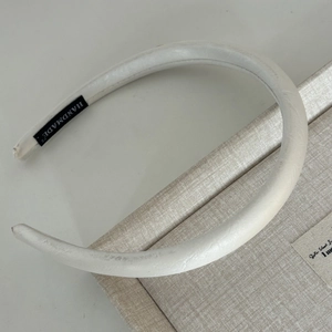 Detail shot of the white satin headband showing the handmade label and soft padded texture