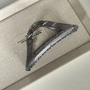 Detail of a large triangular hair claw clip with fine silver glitter and metal spring