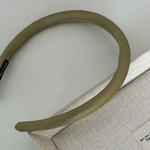 Detailed close-up of olive green textured leather headband with handmade inner label