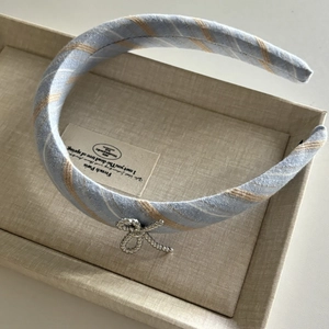 Détail de serre-tête en tissu écossais bleu et blanc avec élégant pendentif nœud argenté