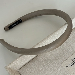 Detail of minimalist milk coffee satin headband featuring a black Handmade woven label