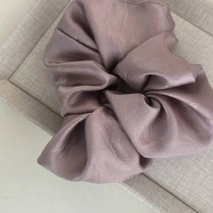 Détail de la texture satinée et des plis du chouchou rose poudré sur le plateau