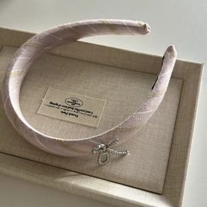 Détail de serre-tête en tissu rayé rose et blanc avec boucle en corde argentée