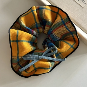 Cute mango yellow checkered scrunchie with a blue denim bow on a light beige surface