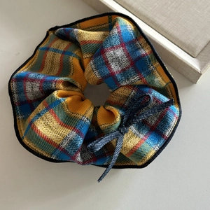 Detail of checkered mango yellow scrunchie with bow decoration and premium fabric texture