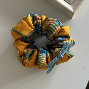 Detailed close-up of yellow plaid scrunchie with denim bow accent and fabric texture