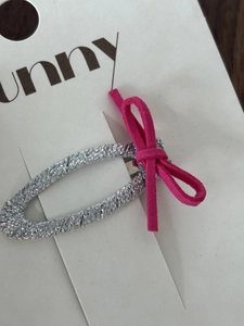 Vista dettagliata di un fermaglio per capelli intrecciato argento con un fiocco in pelle scamosciata rosa