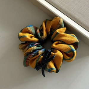 Detail of yellow plaid scrunchie with fine woven texture and small dark blue bow