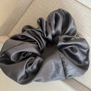 Détail du chouchou en satin gris montrant la texture de soie brillante et les plis élégants