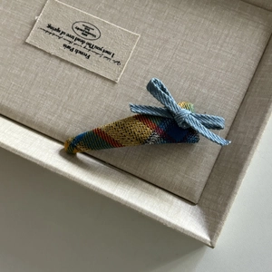 Detailed shot of a vintage plaid hair clip featuring a blue denim bow on soft fabric