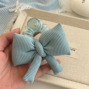 Détail d'un élastique à cheveux nœud bleu clair avec cordon de téléphone à la main